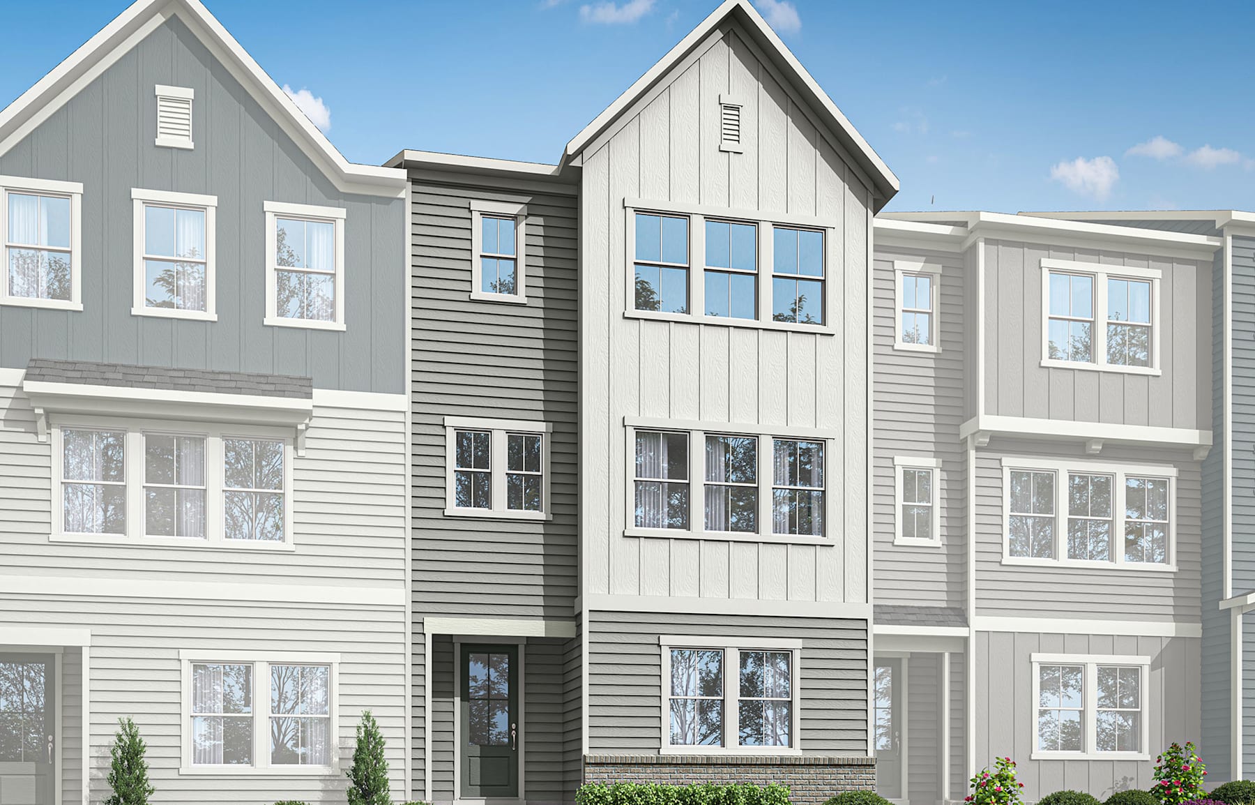 A multi-story residential building with gray and white siding, featuring large windows and a well-manicured lawn in the foreground.