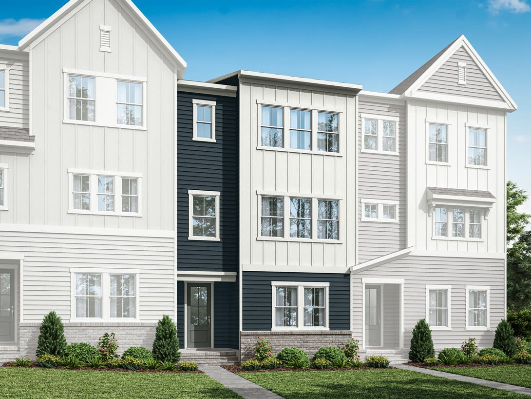 A multi-story residential building with a mix of white and dark gray siding, surrounded by a well-manicured lawn and landscaping.
