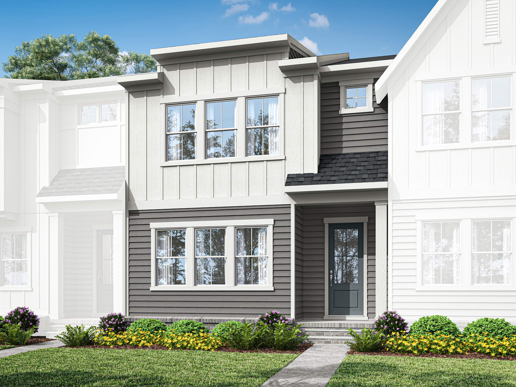 A modern two-story residential building with a white exterior and gray siding, surrounded by a well-manicured lawn and colorful flower beds in the foreground.