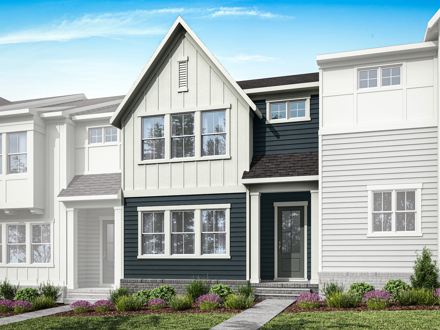 A modern, two-story townhouse with a gabled roof, white siding, and black trim, surrounded by a well-landscaped yard with flowers in the foreground.