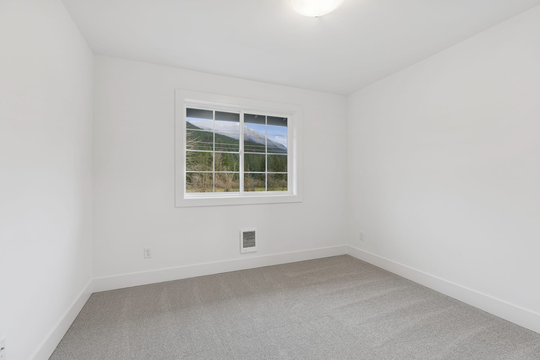 A bright, empty room with a large window overlooking a scenic outdoor landscape.