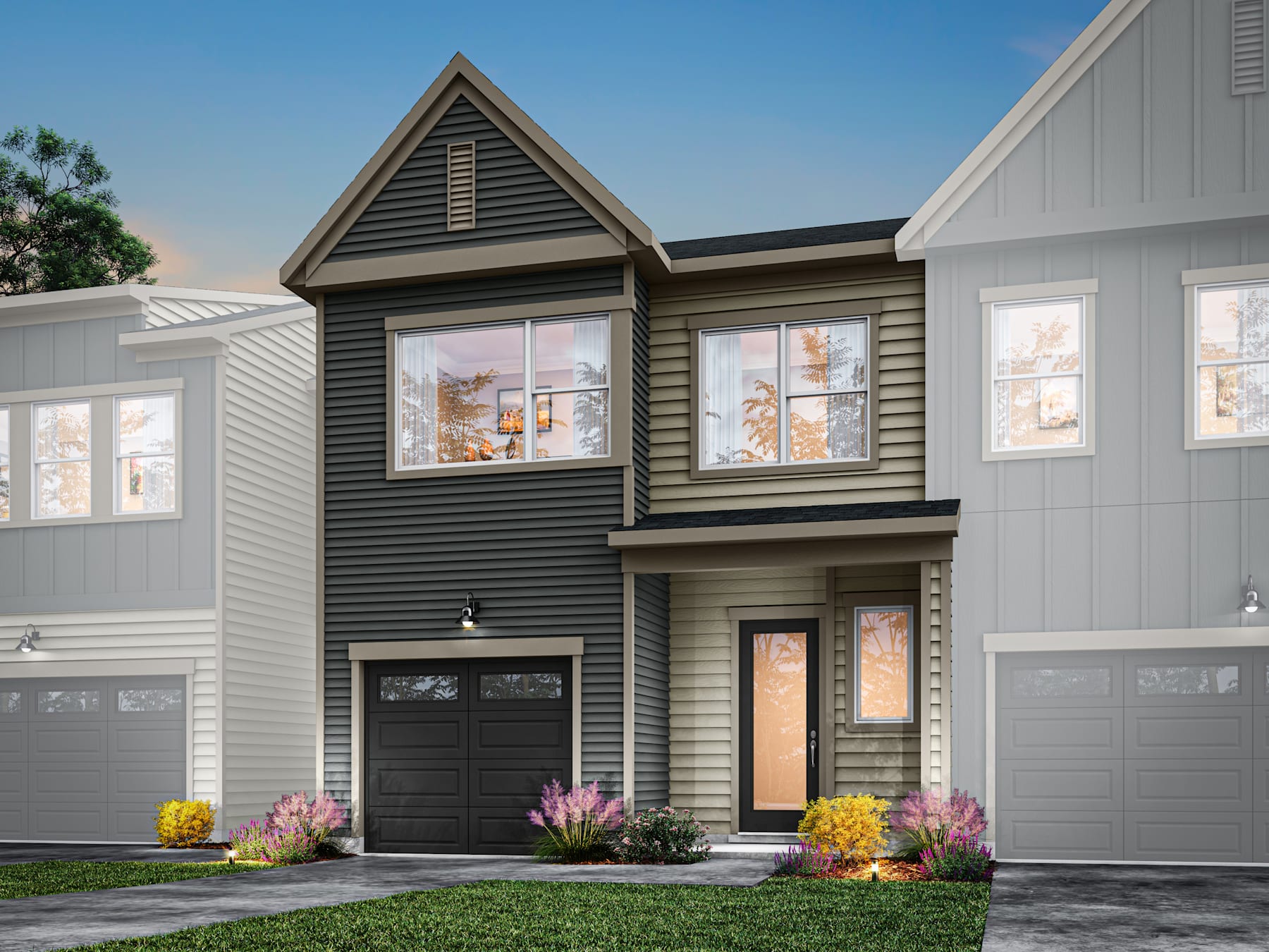 A modern two-story townhouse with a gray exterior, black garage doors, and a colorful flower garden in the foreground.