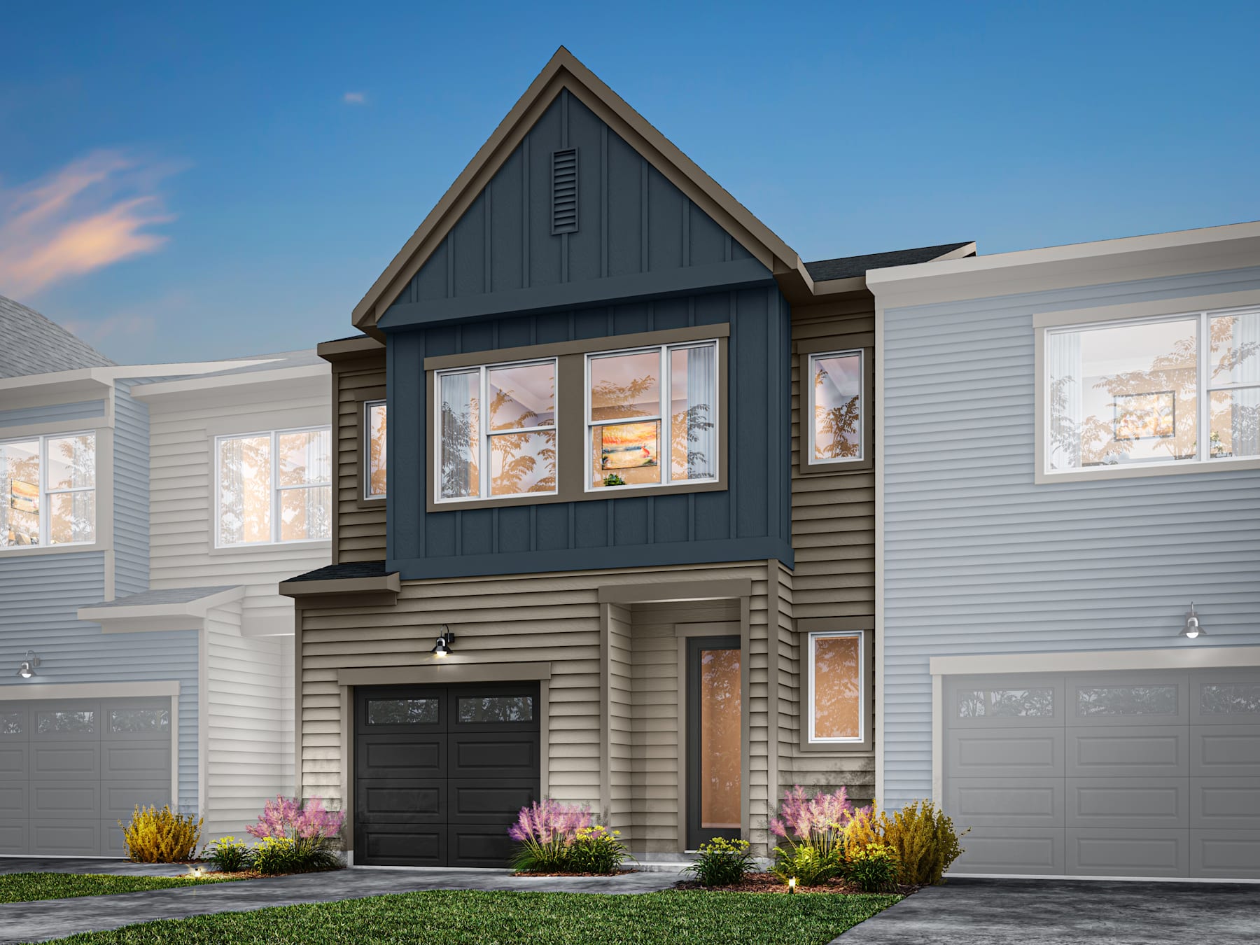 A modern two-story townhouse with a gabled roof, gray siding, and a landscaped front yard featuring colorful flowers.