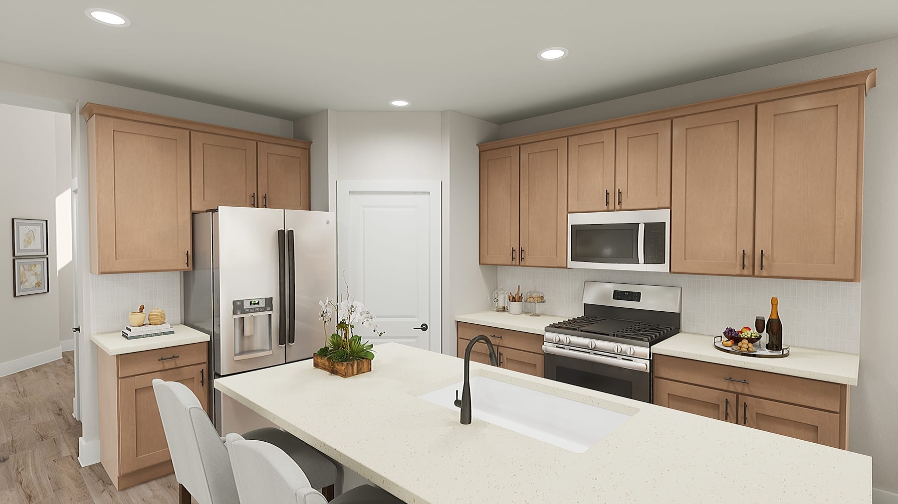 A modern, well-equipped kitchen with light-colored wooden cabinets, stainless steel appliances, and a white countertop island in the foreground.