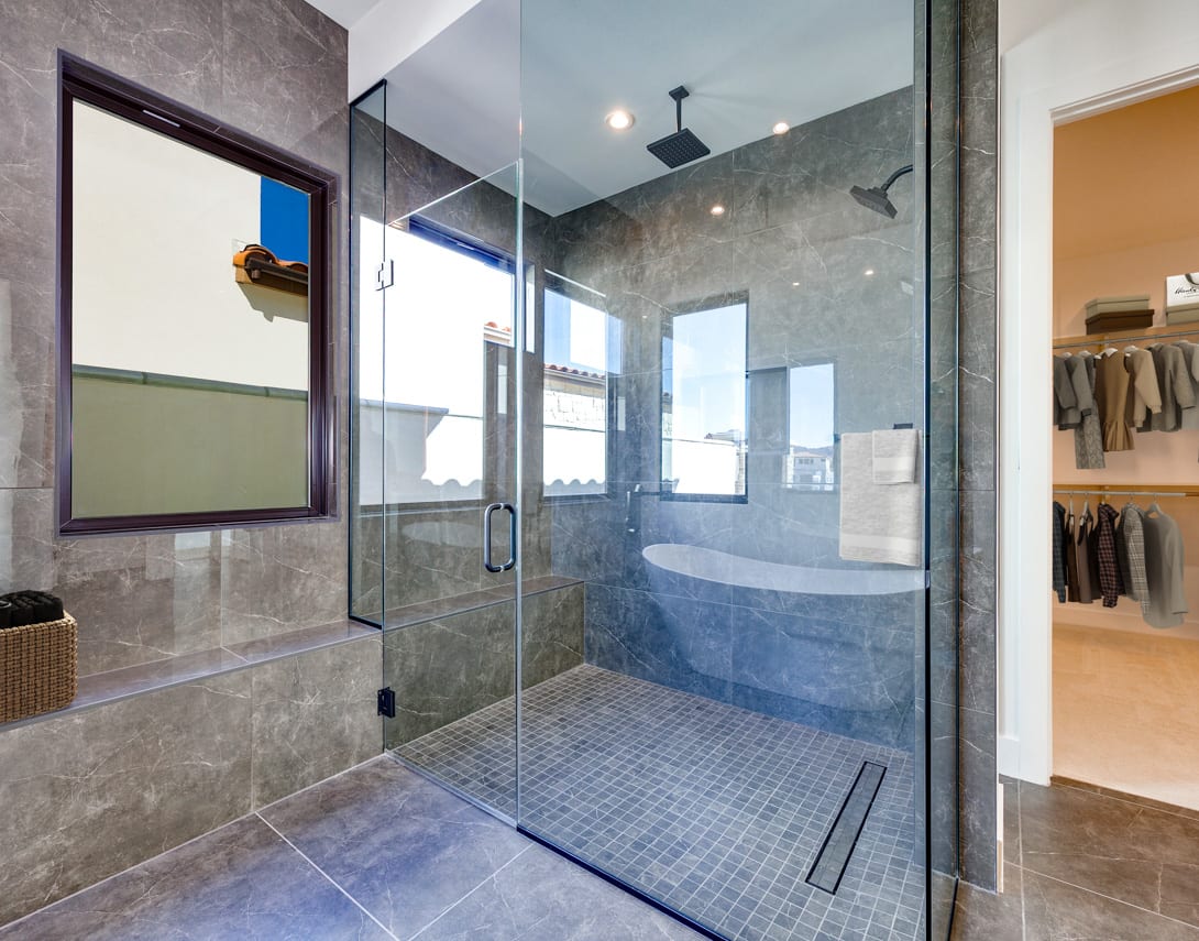 A modern and spacious bathroom with a large glass shower enclosure, a bathtub, and a vanity area with a mirror.