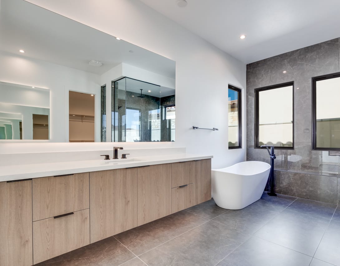A modern and spacious bathroom with a large vanity, a freestanding bathtub, and a glass-enclosed shower area, all set against a backdrop of neutral-toned tiles and walls.