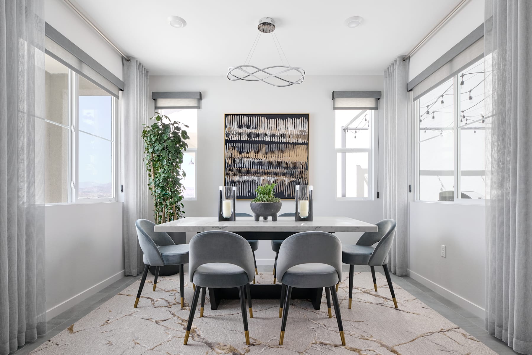 A modern and minimalist dining room with a rectangular table, gray chairs, and a large abstract artwork on the wall, surrounded by large windows and potted plants.