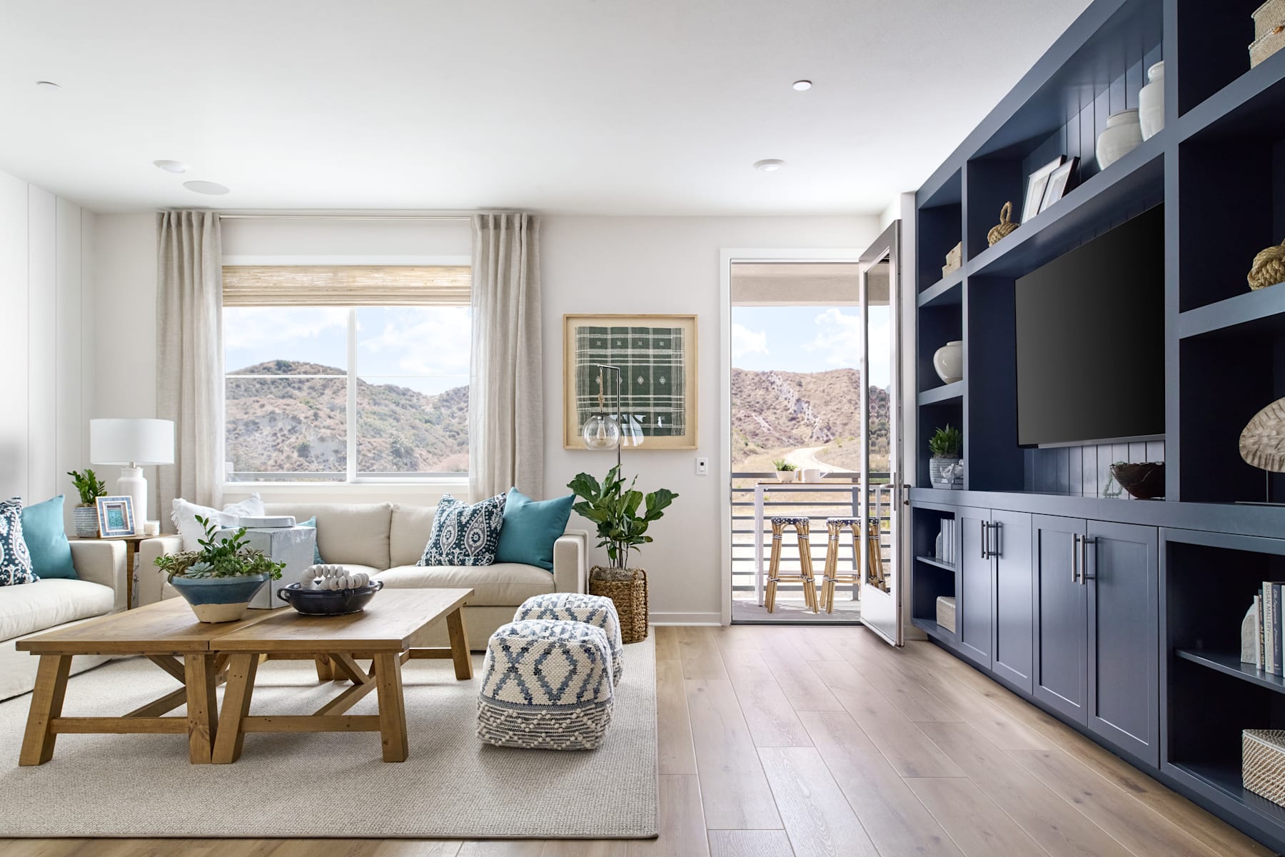 A cozy and inviting living room with a wooden dining table, plush seating, and a large window overlooking a scenic mountain landscape.