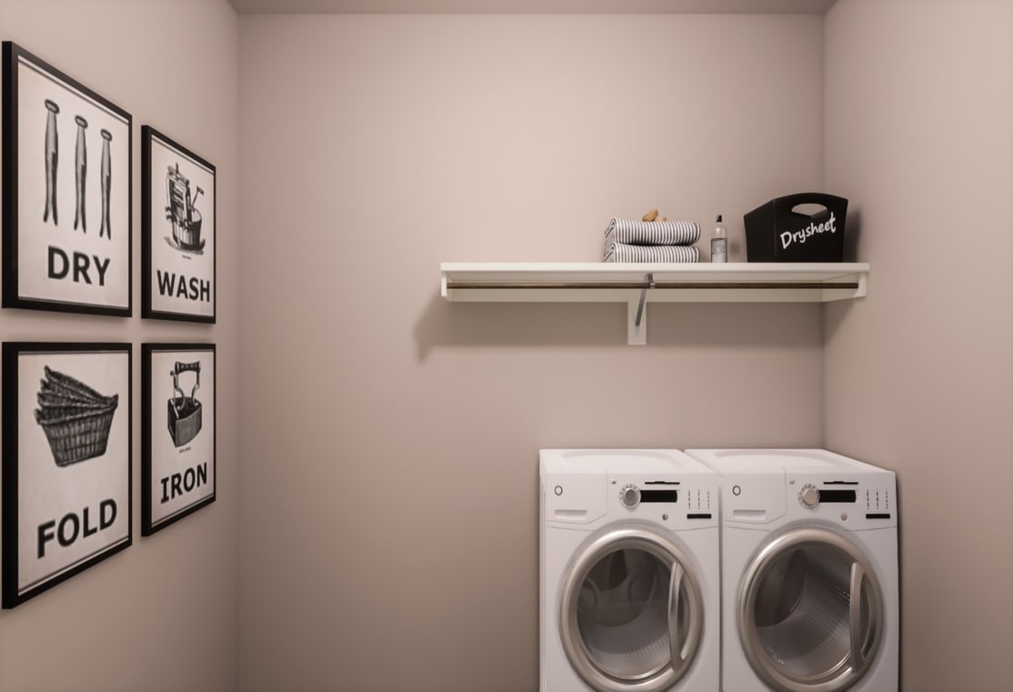 A small laundry room with a white washer and dryer, shelves, and framed artwork on the walls.