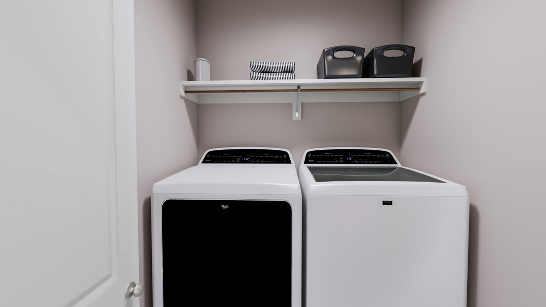 The image shows a laundry room with two white washing machines in the foreground and shelves with various household items in the background.