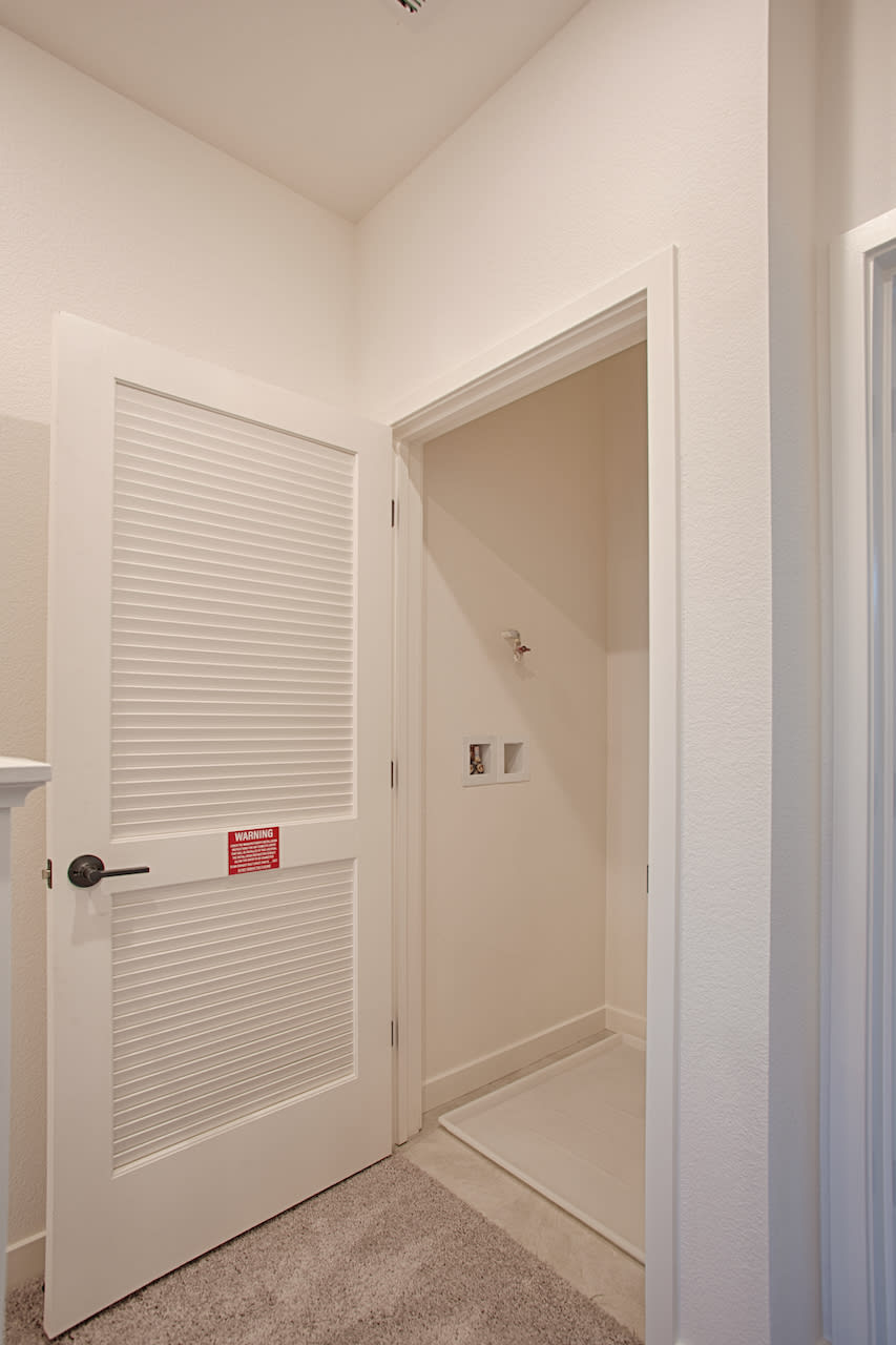 A simple, minimalist interior with a white door, a white wall, and a carpeted floor, creating a clean and uncluttered atmosphere.