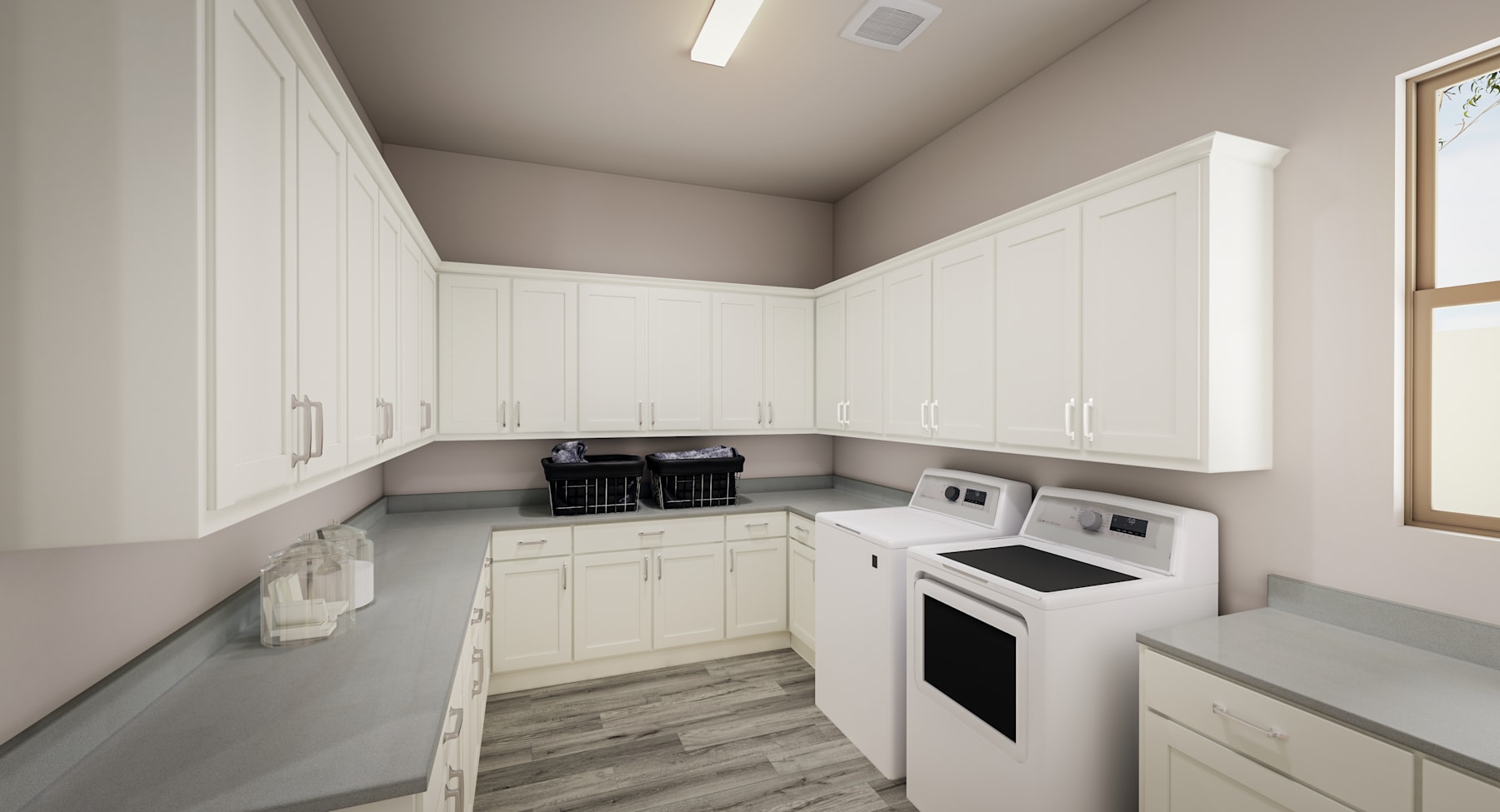 A modern, well-organized laundry room with white cabinets, a washing machine, and a dryer set against a neutral-colored wall.