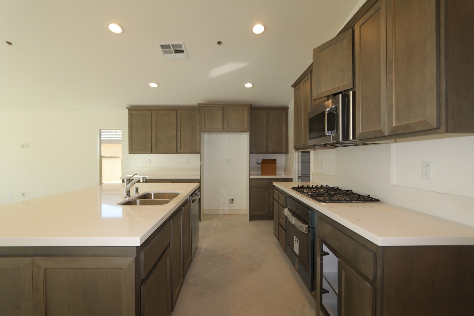 A modern and spacious kitchen with wooden cabinets, white countertops, and stainless steel appliances.