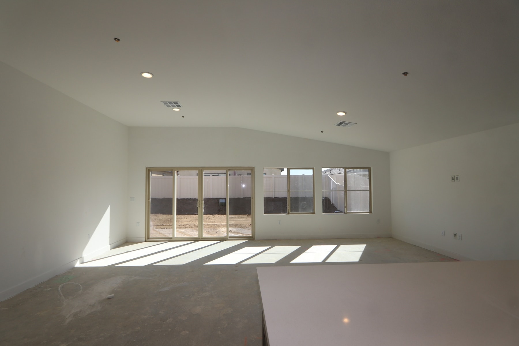 An empty, bright room with large windows allowing natural light to stream in, creating a spacious and minimalist atmosphere.