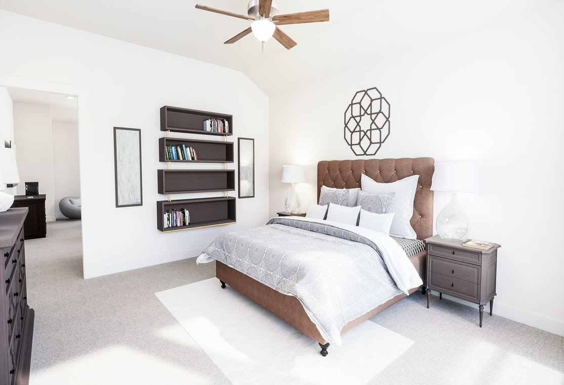 A cozy and well-designed bedroom with a large bed, wooden furniture, and decorative wall art, all illuminated by a ceiling fan.