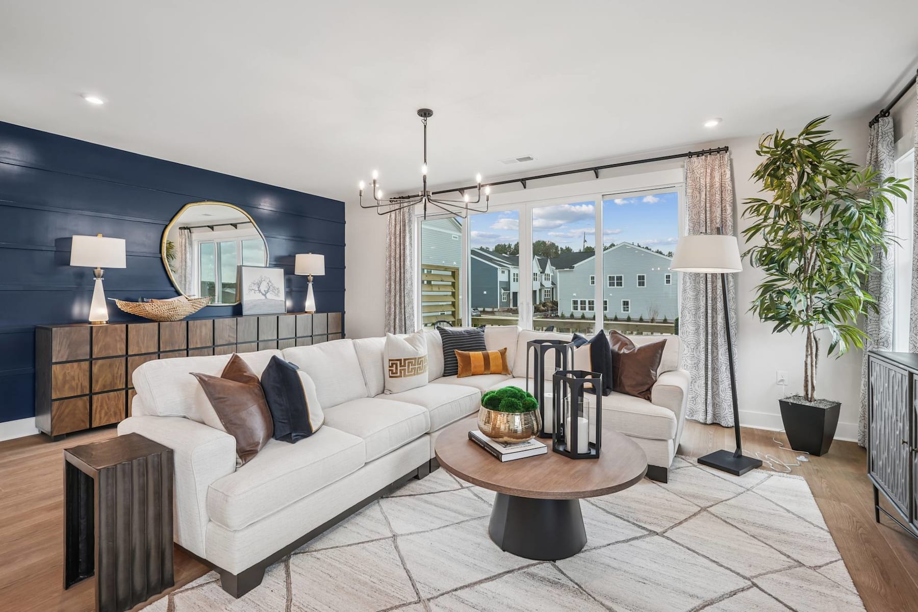 A cozy and modern living room with a white sofa, wooden coffee table, and a large window overlooking a scenic outdoor view.