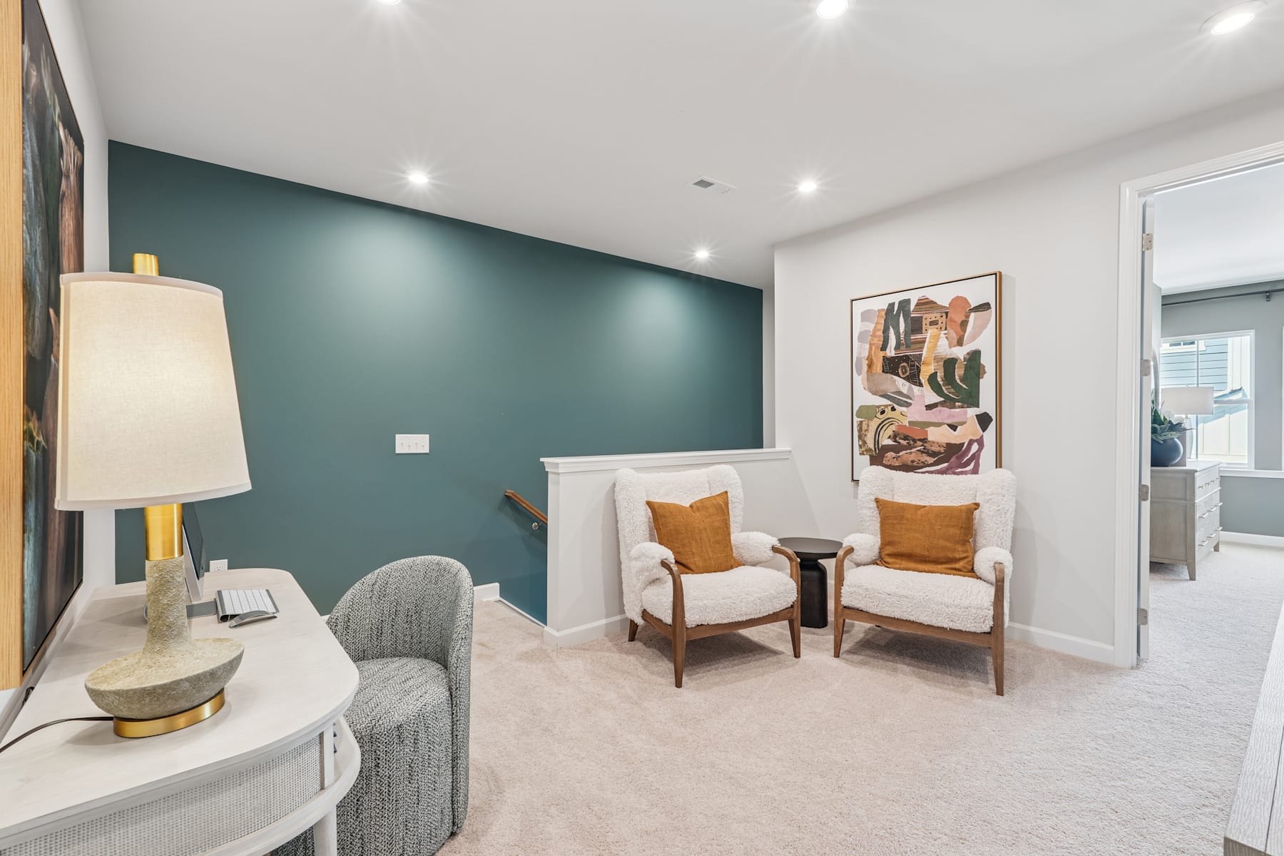 The image depicts a cozy and inviting living room space with a white sofa, two armchairs, and a decorative wall art piece. The room features a neutral color palette with a touch of green on one of the walls, creating a warm and calming atmosphere.