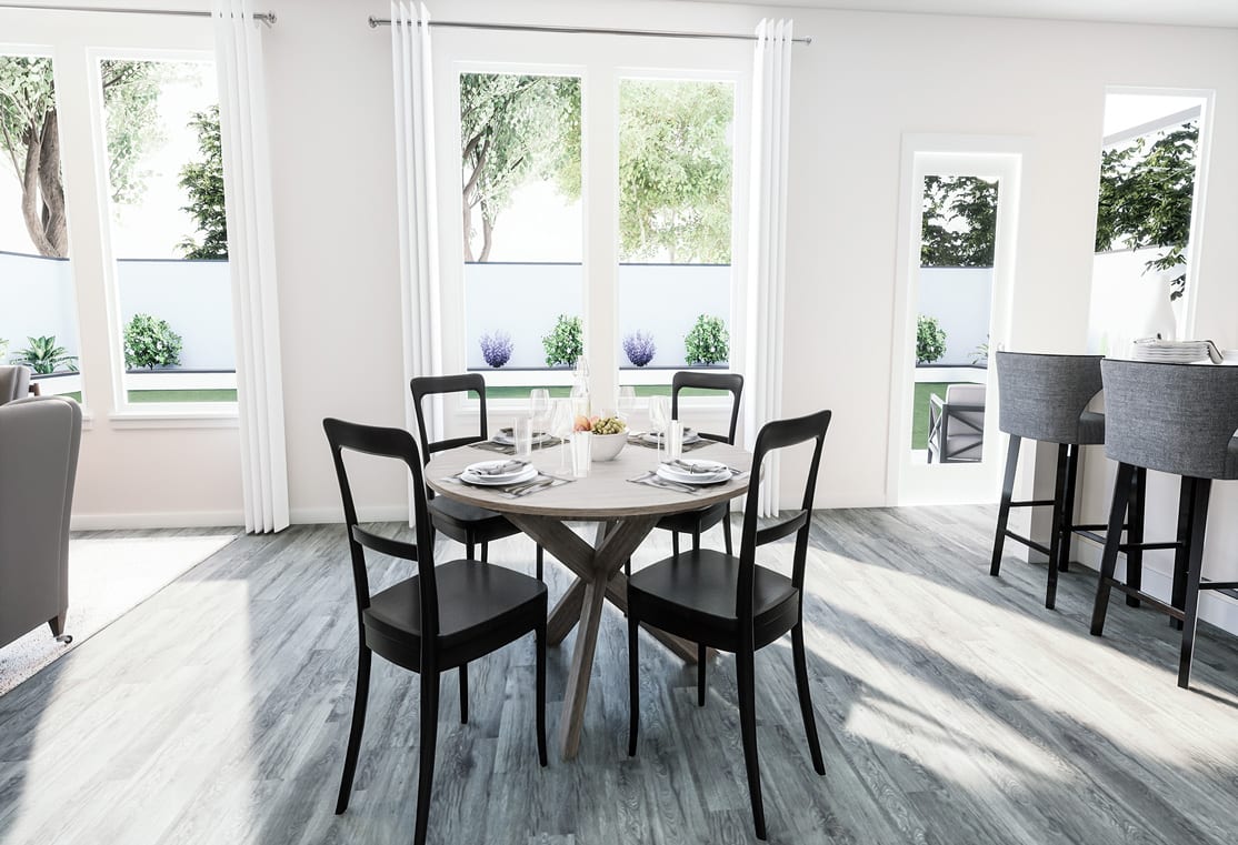 A modern and minimalist dining area with a round wooden table, black chairs, and large windows overlooking a lush outdoor environment.