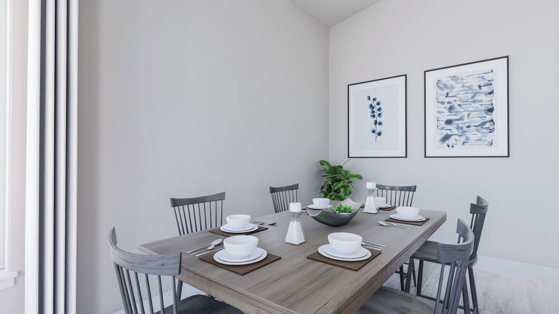 A minimalist dining area with a wooden table, gray chairs, and framed artwork on the walls, complemented by a potted plant and tableware.
