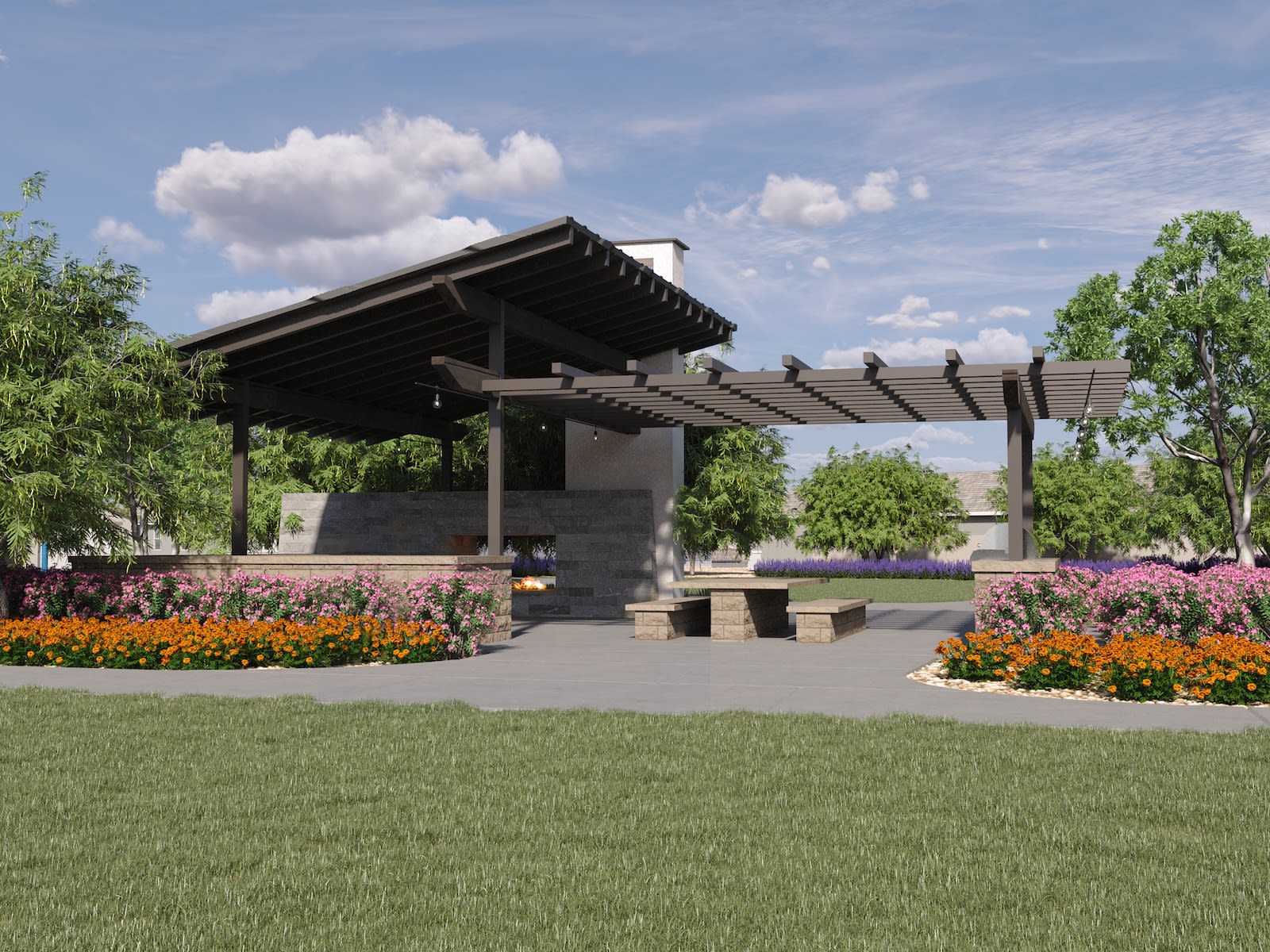 A covered pavilion structure with a tiled roof stands in a well-manicured garden, surrounded by lush greenery and vibrant flower beds under a cloudy blue sky.