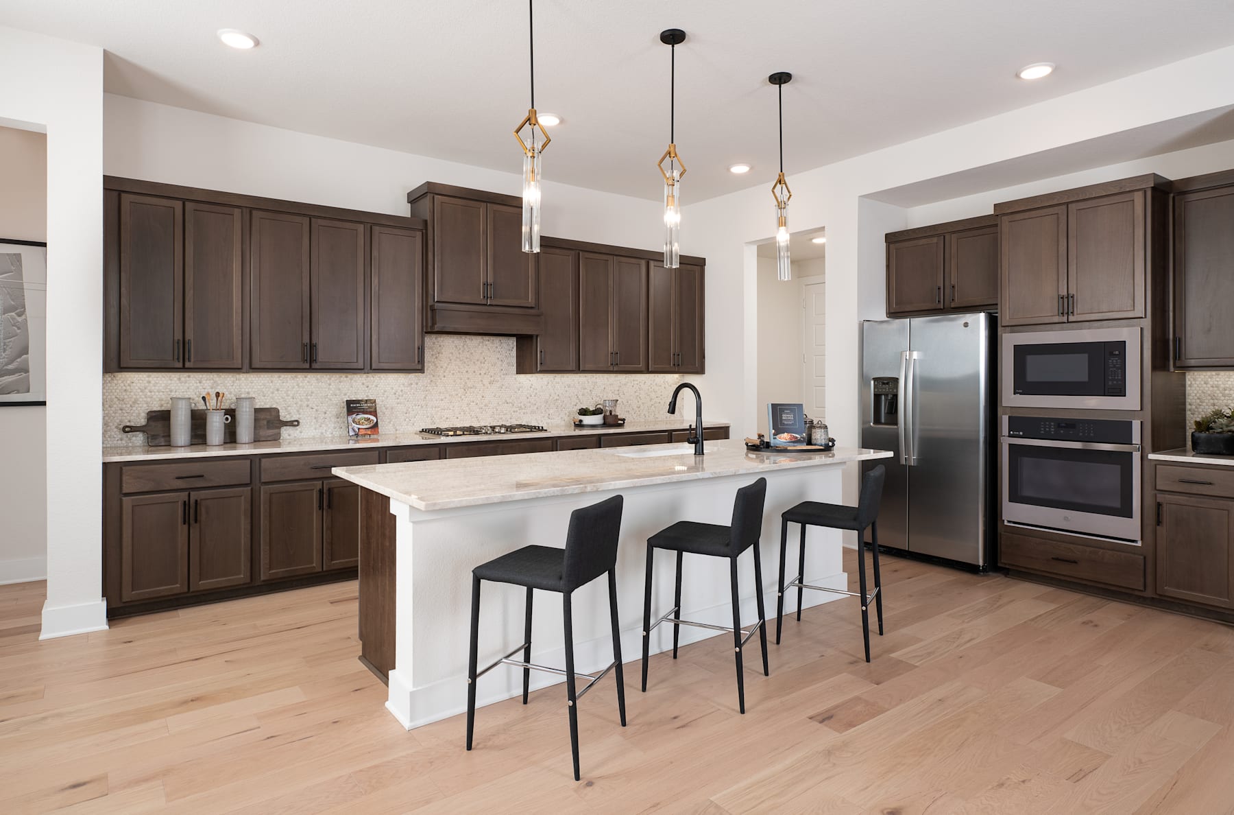 A modern and spacious kitchen with dark wood cabinets, a white countertop, and pendant lights hanging above the island.