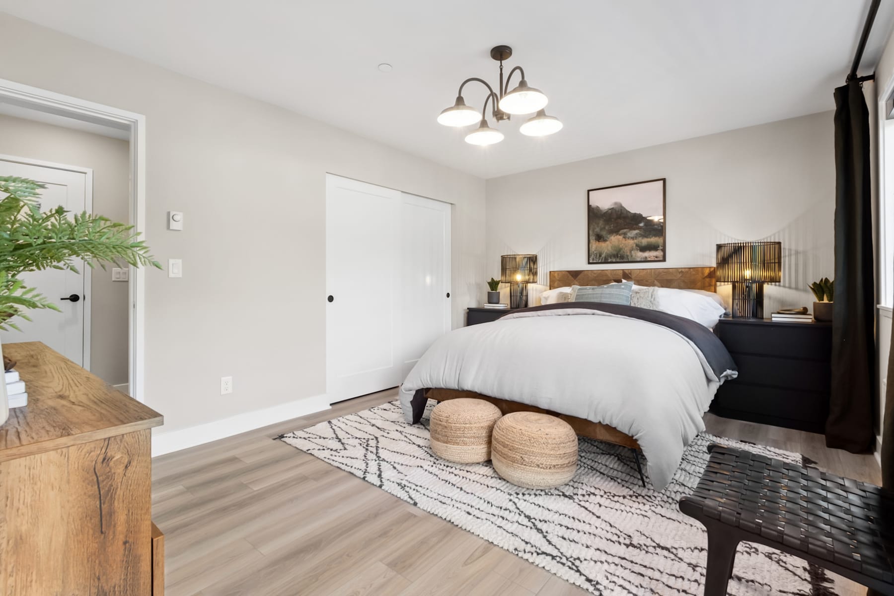 A cozy and well-designed bedroom with a large bed, wooden furniture, and decorative elements such as a patterned rug and a chandelier.