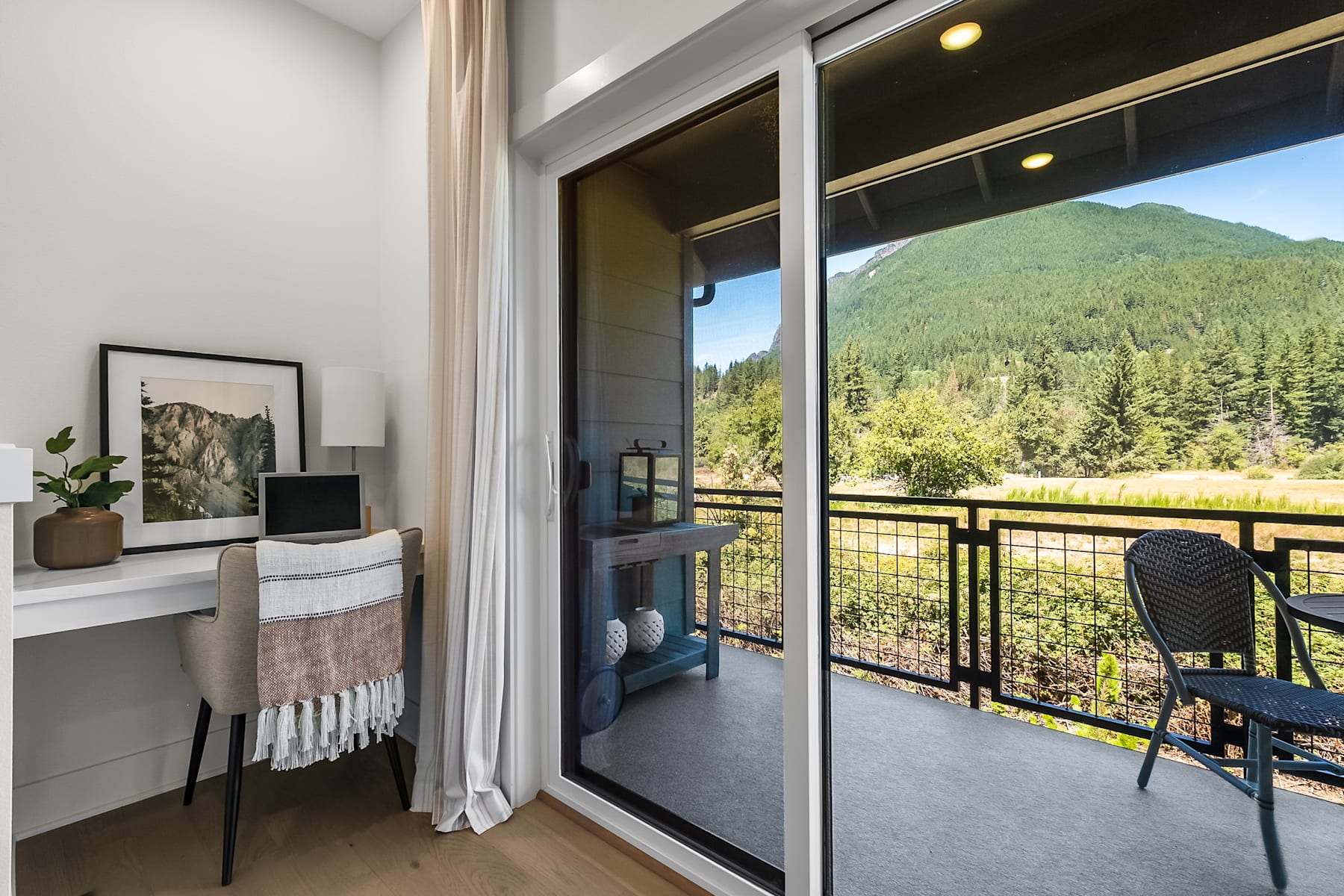 A cozy and inviting indoor space with a large window overlooking a lush, forested landscape in the background.