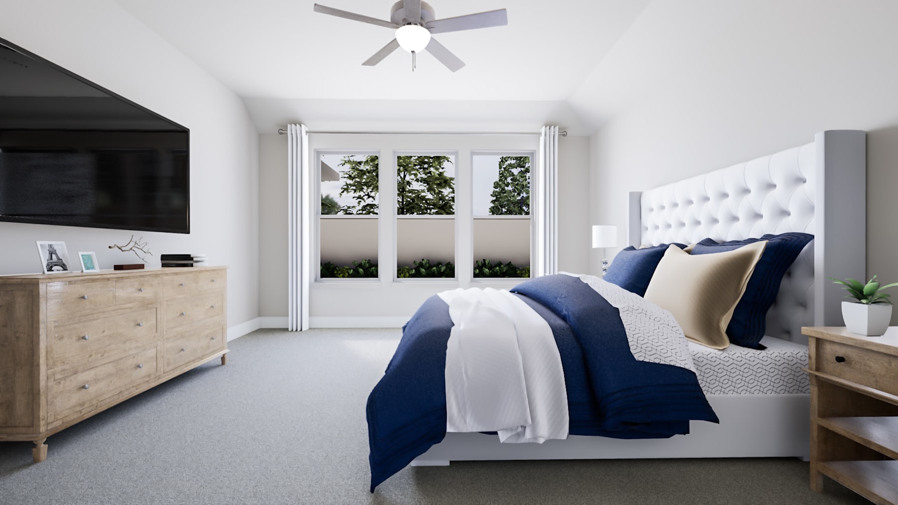 A cozy and modern bedroom with a white tufted headboard, navy blue bedding, and a wooden dresser against the wall. The room features large windows overlooking greenery outside, and a ceiling fan provides a touch of elegance.
