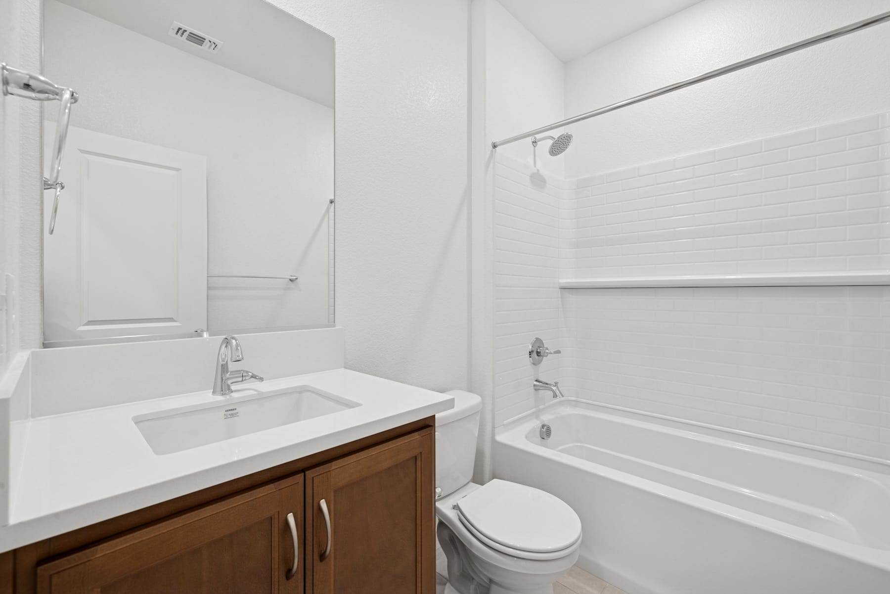 A modern, minimalist bathroom with a white vanity, a bathtub, and a toilet, all set against a clean, bright backdrop.