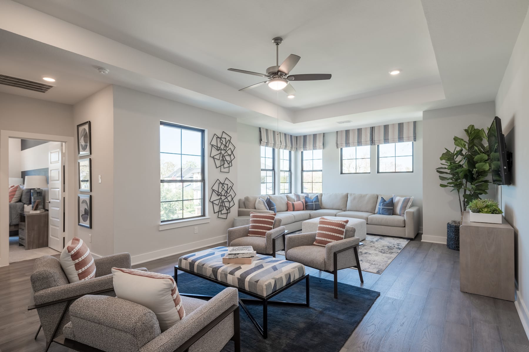 A cozy and well-furnished living room with a comfortable sectional sofa, armchairs, and a patterned rug, complemented by large windows that allow natural light to flood the space.