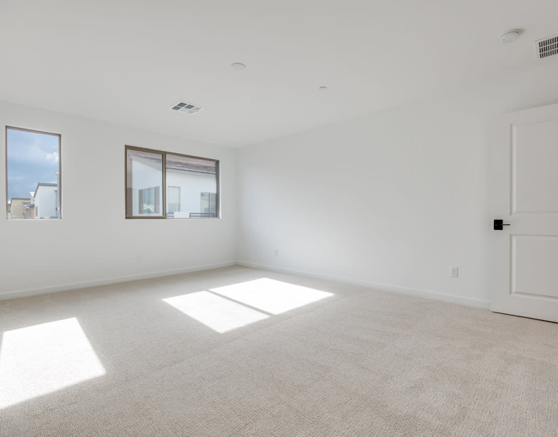 A spacious, well-lit room with a neutral color scheme, featuring a large window and a minimalist design.