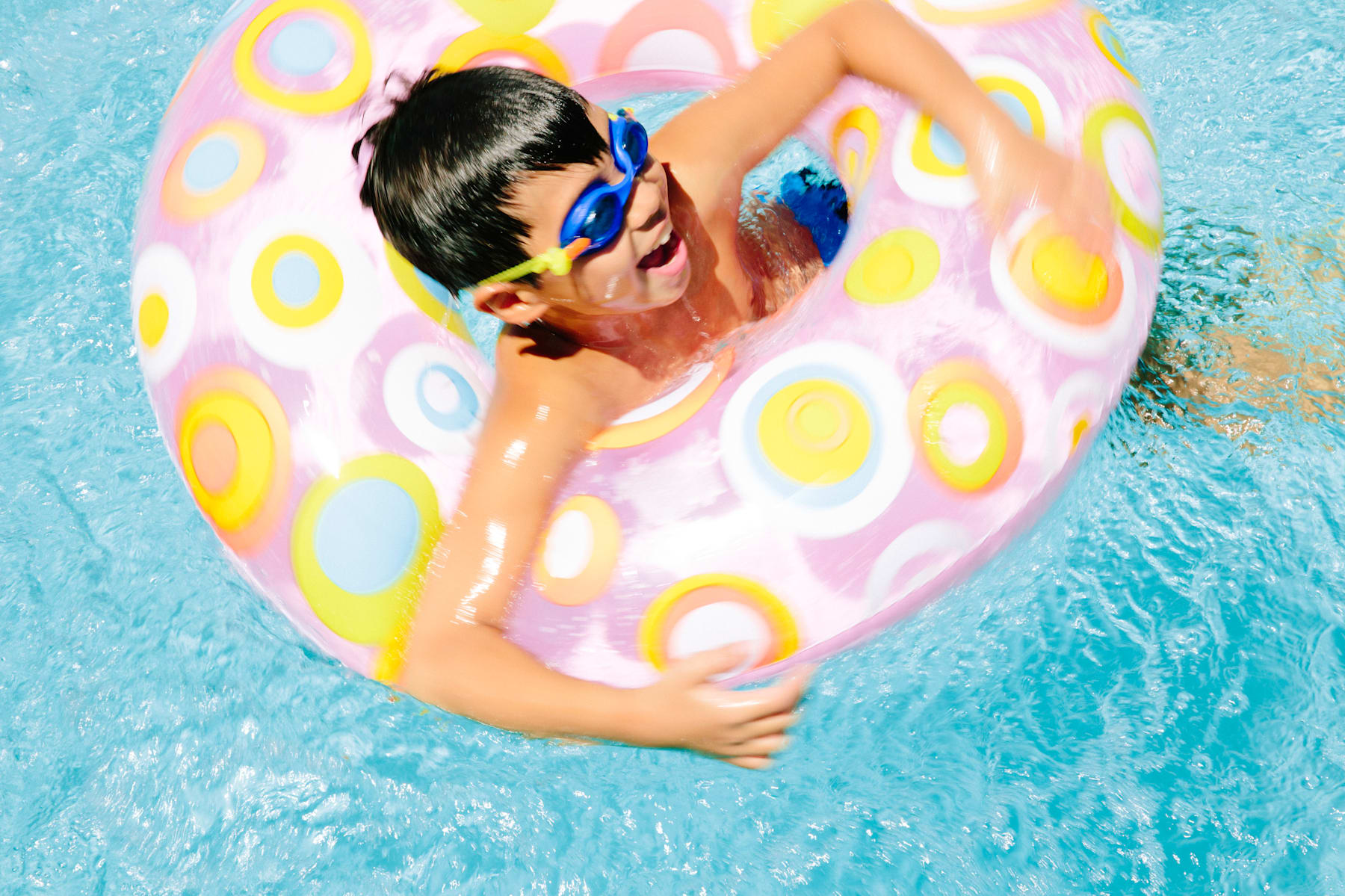 A person in a colorful, patterned inflatable float relaxing in a swimming pool.