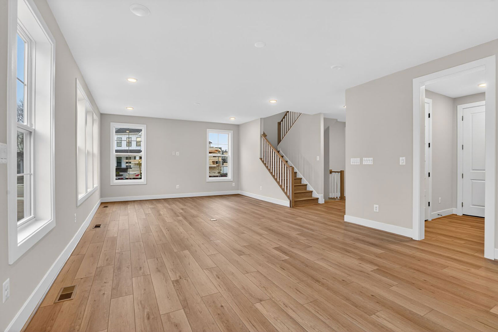 A spacious and bright living room with hardwood floors, a staircase, and a window providing natural light.