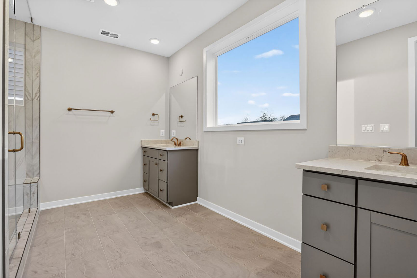 A modern and well-lit bathroom with a vanity, sink, and a large window overlooking the outdoors.