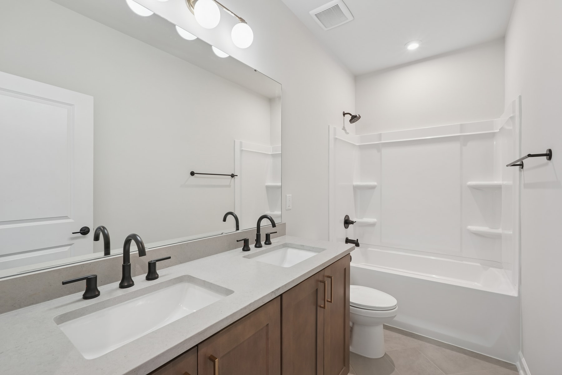 A modern and minimalist bathroom with white walls, dual vanity sinks, and black fixtures, creating a clean and sleek aesthetic.