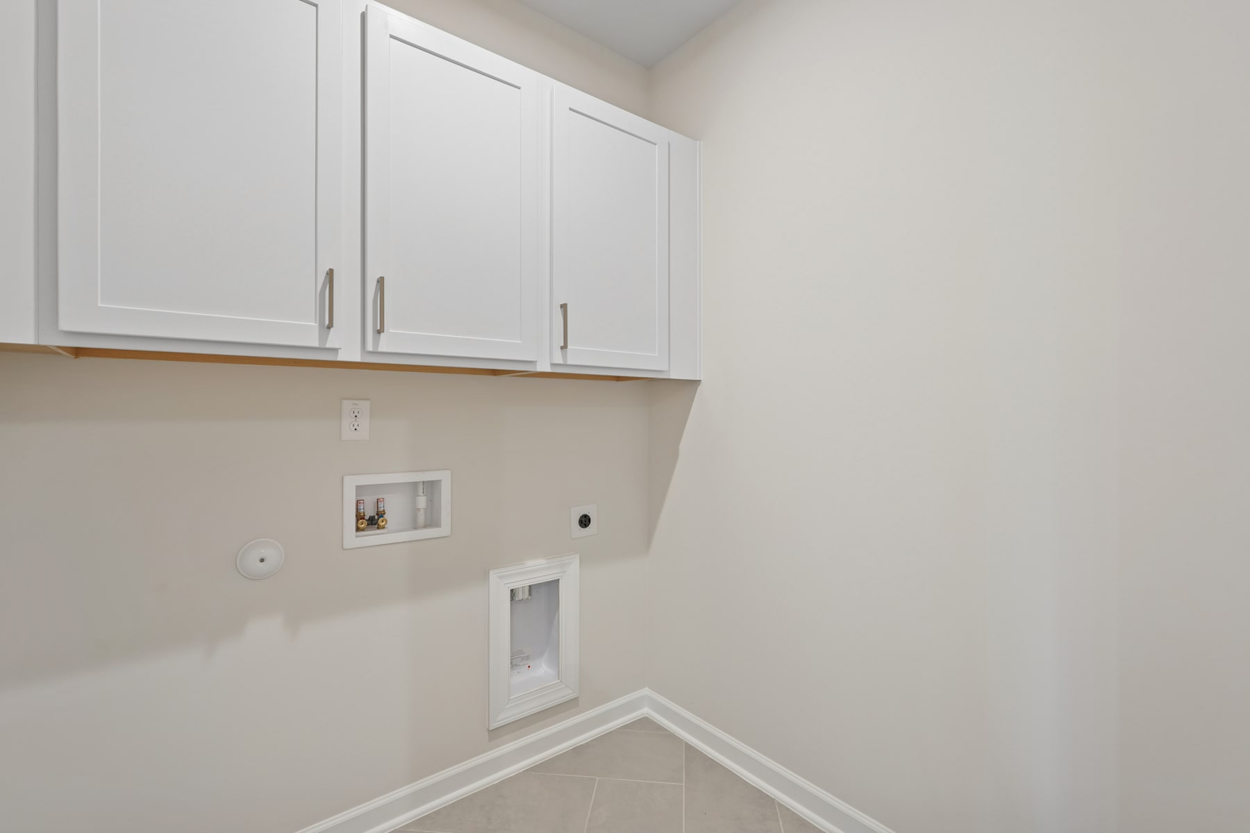 The image shows a small, narrow hallway with white cabinets and a light-colored wall. There is a light switch and an electrical outlet visible on the wall.