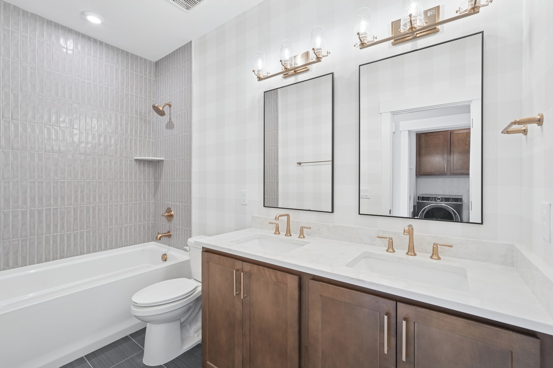 A modern and well-designed bathroom with a double vanity, a large mirror, and a bathtub, featuring a clean and minimalist aesthetic.