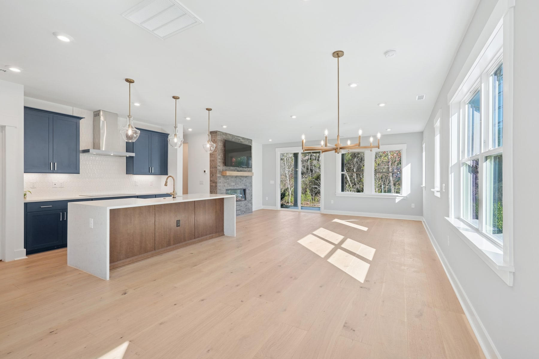 A spacious and bright open-concept kitchen and living area with hardwood floors, modern cabinetry, and large windows providing ample natural light.