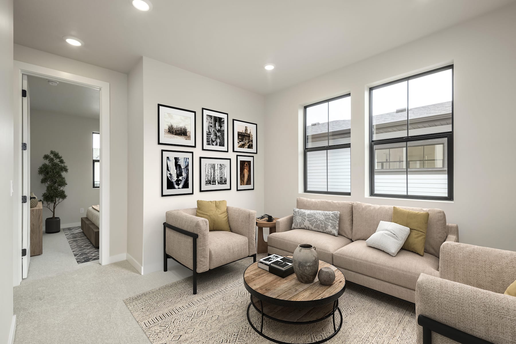 A cozy and modern living room with a comfortable sofa, armchair, and a round wooden coffee table, surrounded by framed artwork on the walls.