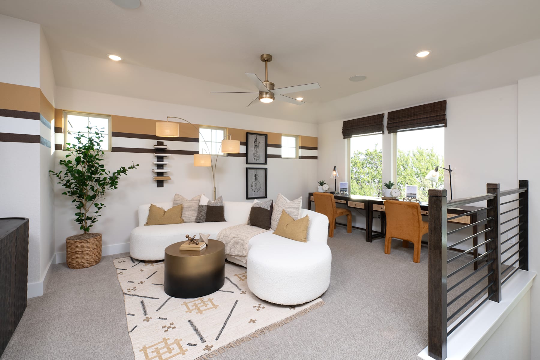 A cozy and modern living room with a comfortable white sofa, a patterned rug, and a wooden dining table in the background, surrounded by shelves and decor elements.