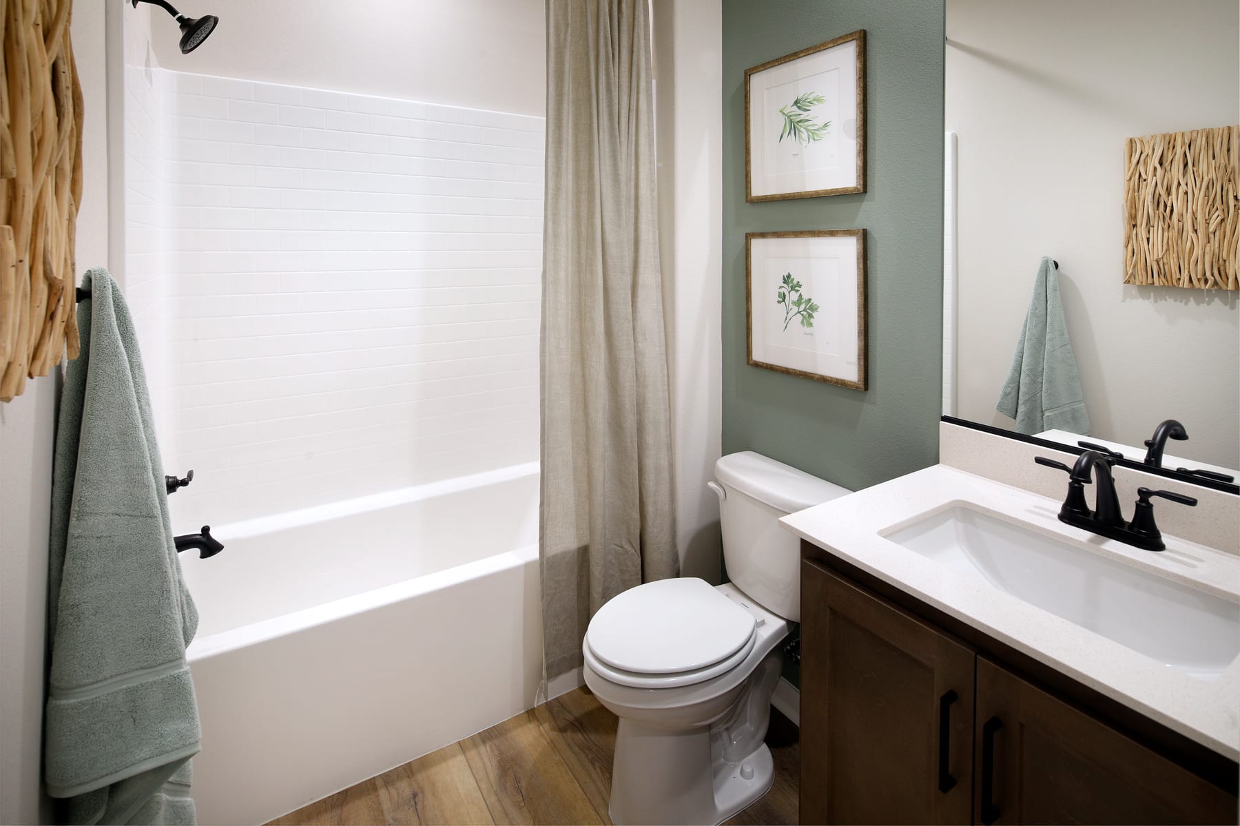 A cozy bathroom with a white bathtub, a wooden vanity, and framed artwork on the walls, creating a warm and inviting atmosphere.