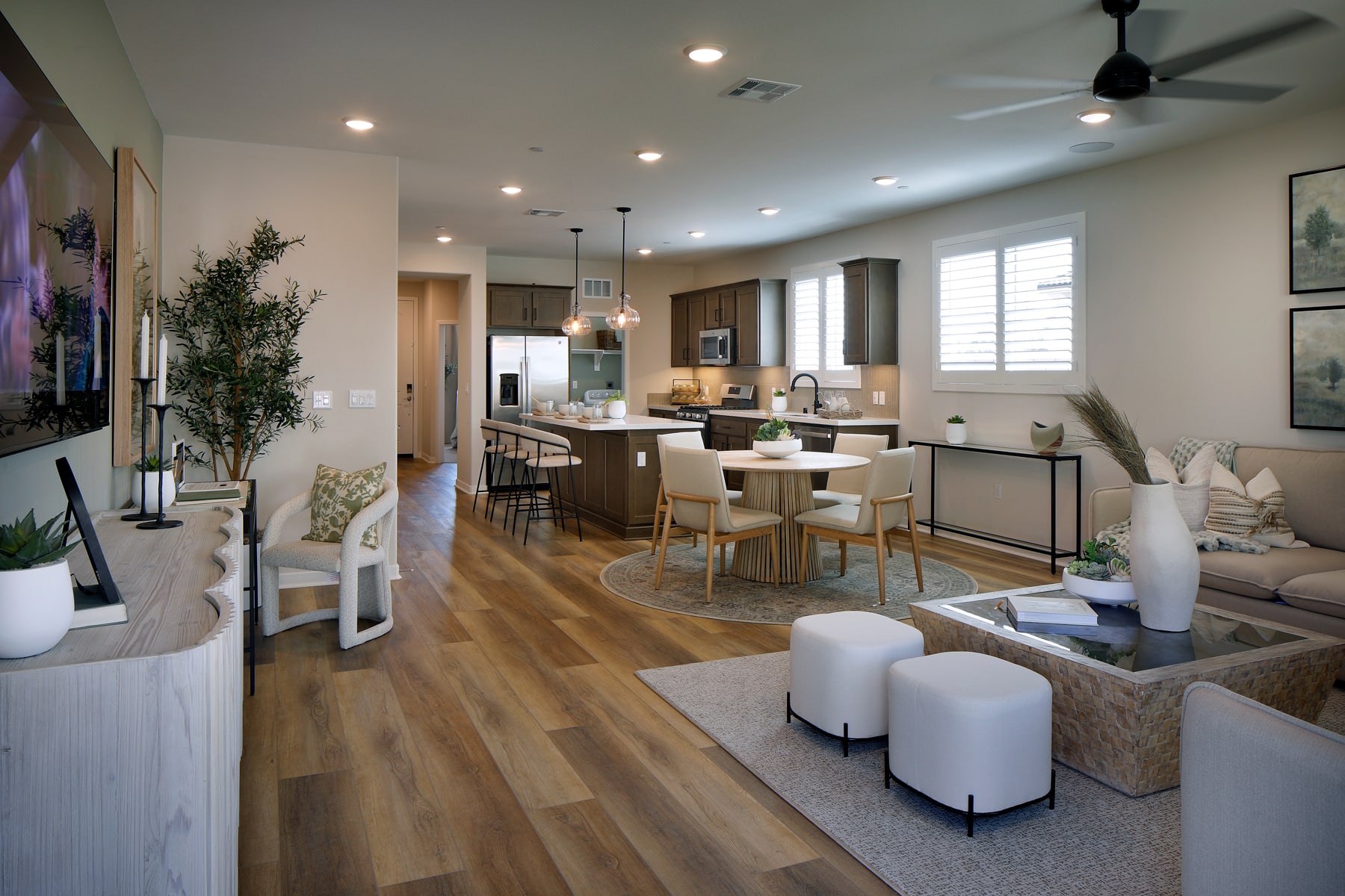 A spacious and modern open-concept living area with a kitchen, dining, and living room, featuring hardwood floors, neutral-toned furniture, and decorative elements.