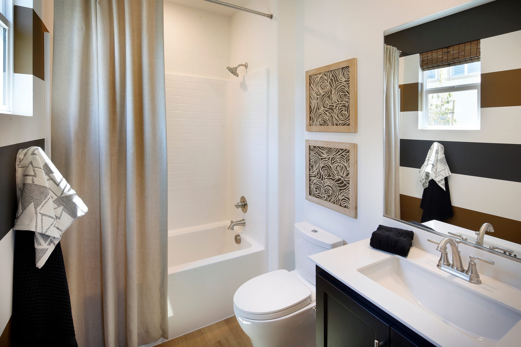 A modern and minimalist bathroom with a white bathtub, a vanity with a sink, and framed artwork on the walls.