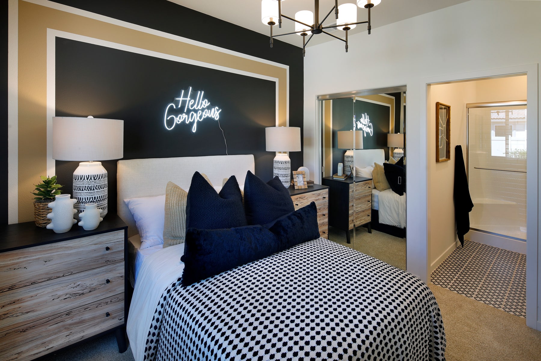 A cozy and stylish bedroom with a black and white checkered pattern on the bedding, a neon sign on the wall, and various decorative elements throughout the space.