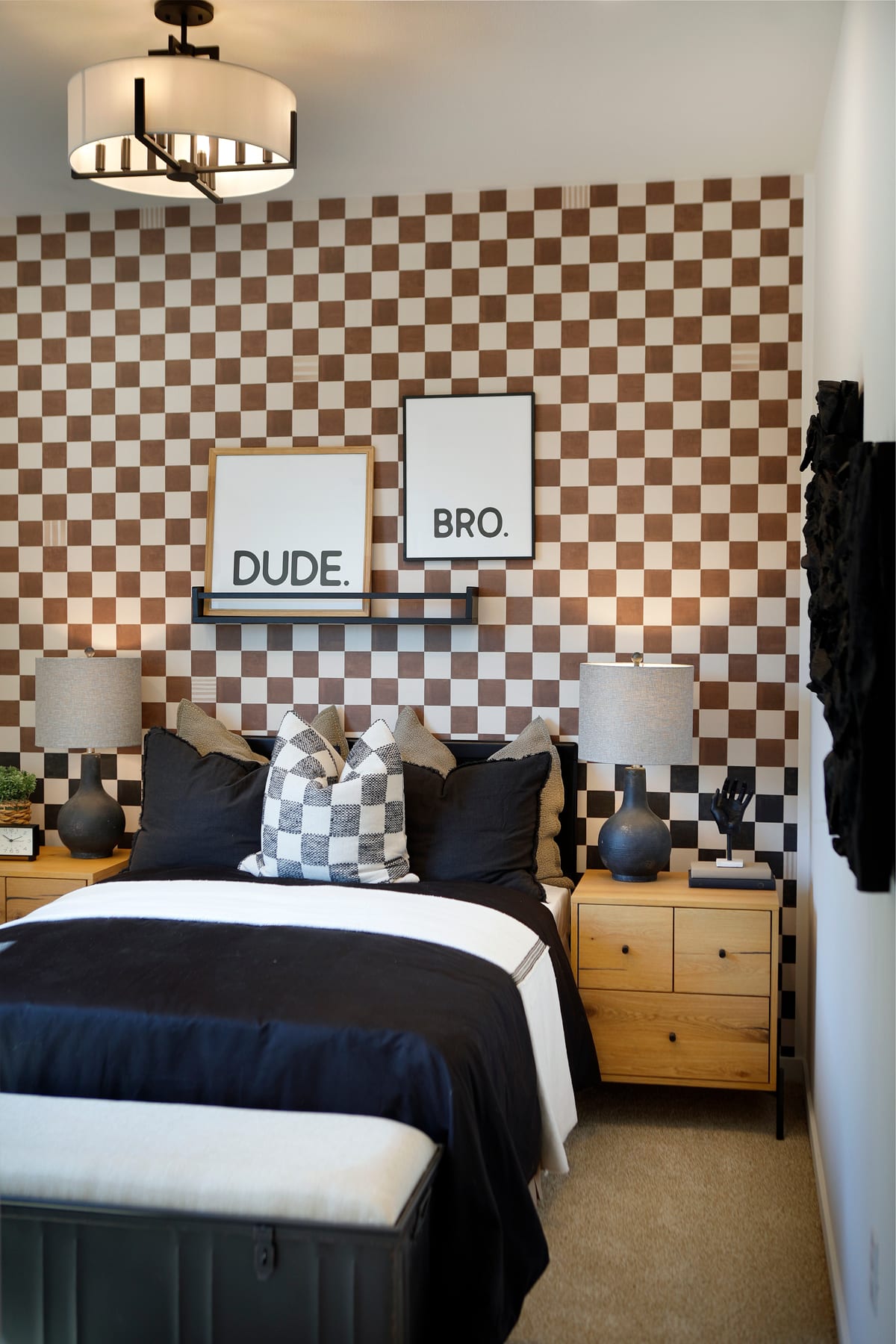A modern and stylish bedroom with a checkered wall pattern, a large bed with dark bedding, and decorative pillows and lamps.