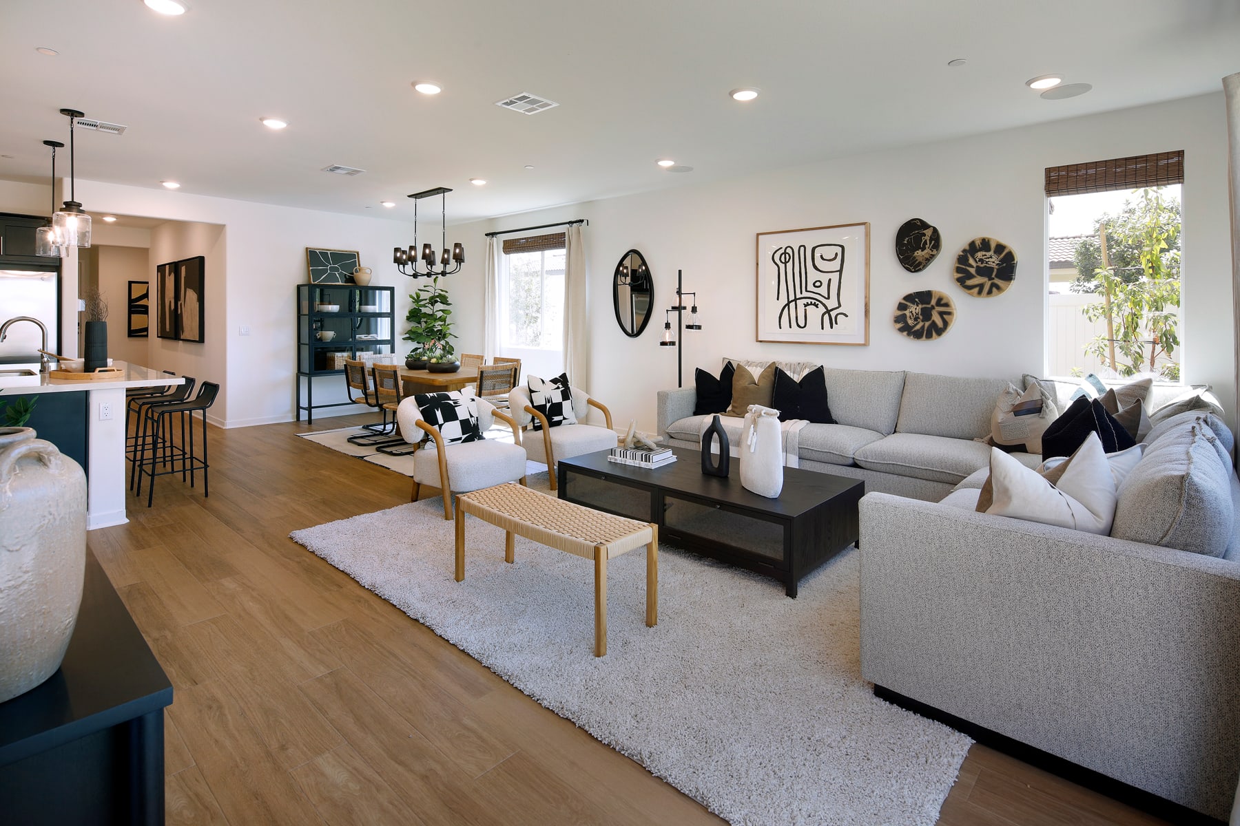 A cozy and stylishly decorated living room with plush gray sofas, a wooden coffee table, and various decorative elements such as wall art and plants, creating a warm and inviting atmosphere.