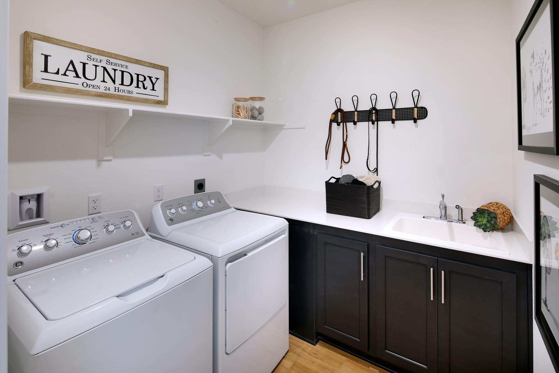 A well-organized laundry room with a washing machine, dark cabinets, and a decorative "Laundry" sign on the wall.