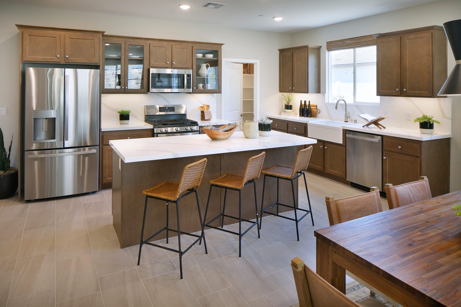 A modern and spacious kitchen with wooden cabinets, stainless steel appliances, a large island with bar stools, and a bright and airy atmosphere.