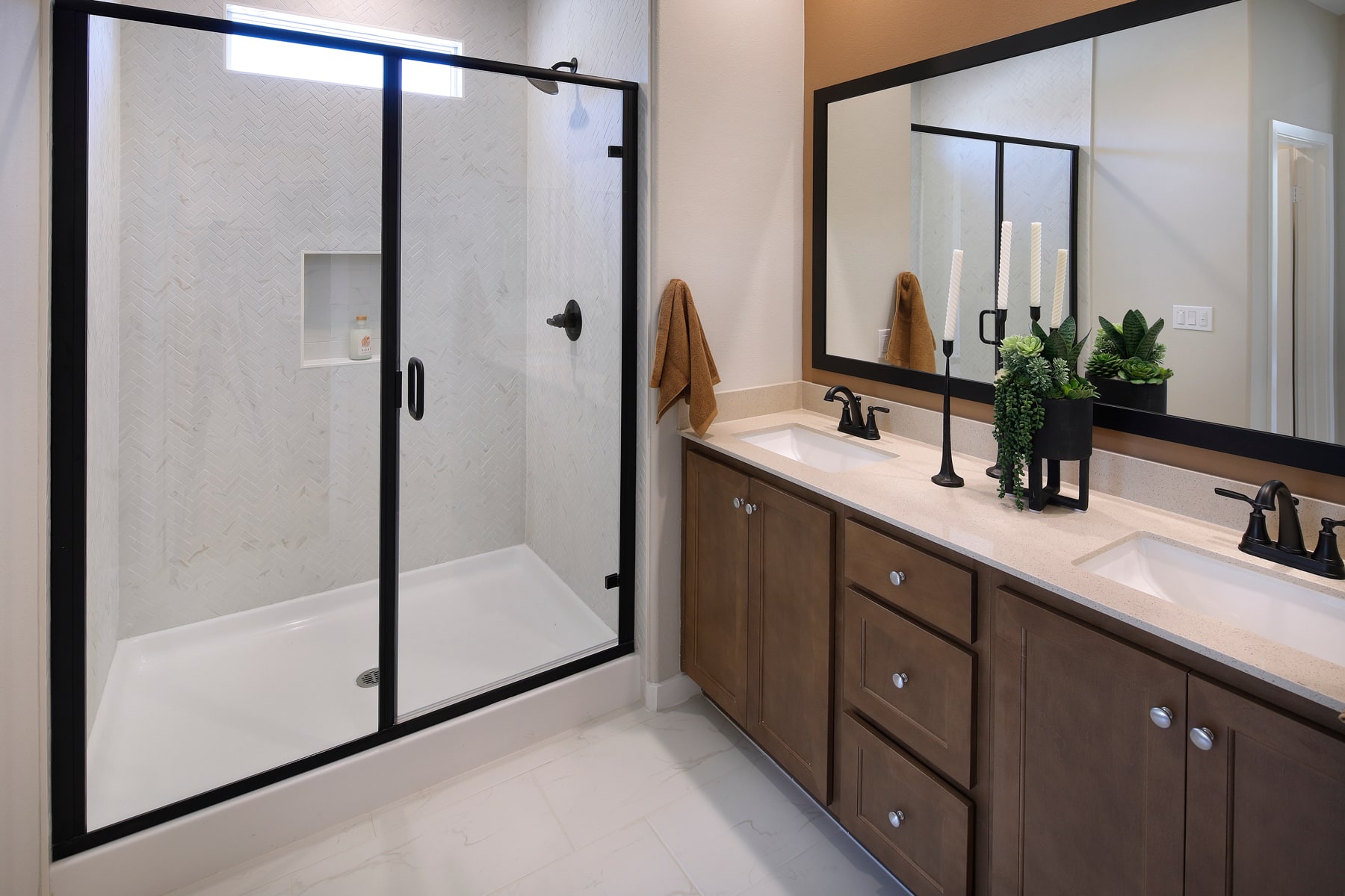 A modern bathroom with a glass shower enclosure, a wooden vanity with drawers, and a large mirror on the wall.