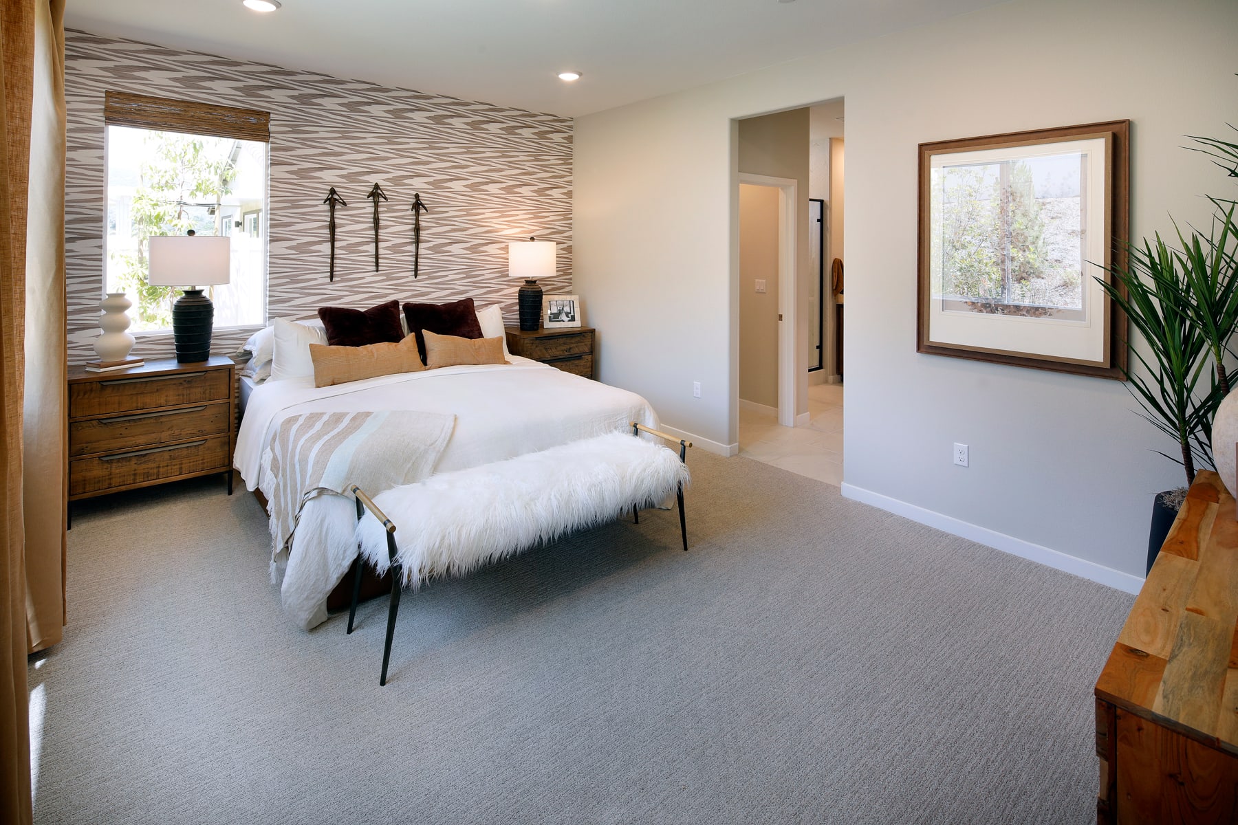 A cozy and inviting bedroom with a plush white bedding, wooden furniture, and a textured accent wall, creating a warm and modern atmosphere.